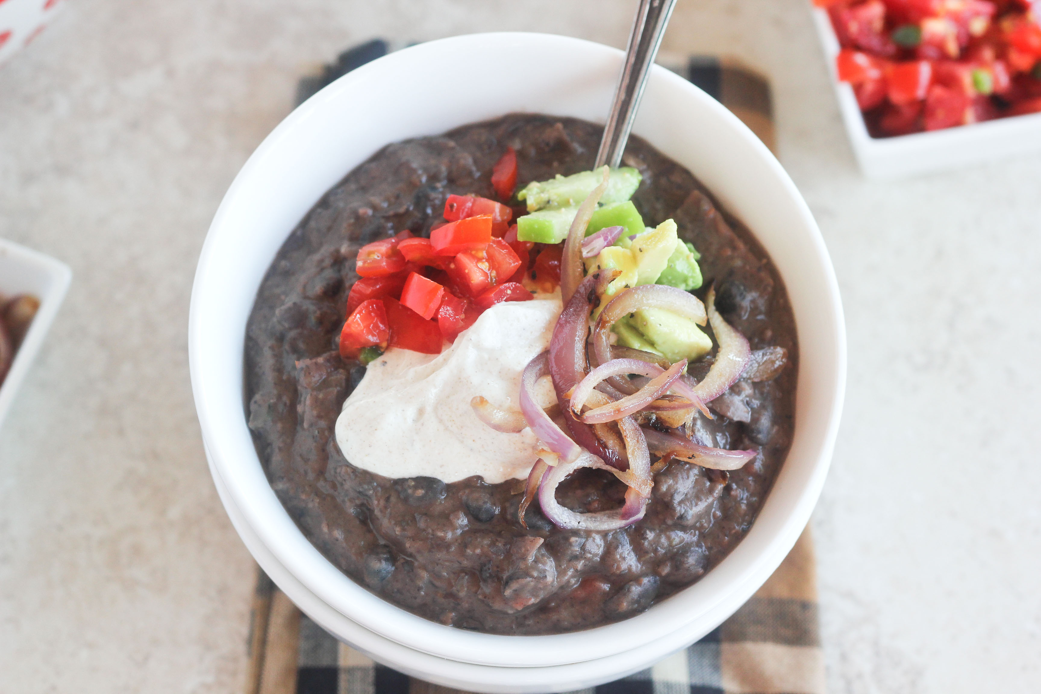 An image depicting the delicious Black Bean Soup recipe featuring toasted crema and three relishes.